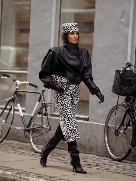 Nina i sort skinnjakke, prikkete hatt og skjørt og sorte støvletter.