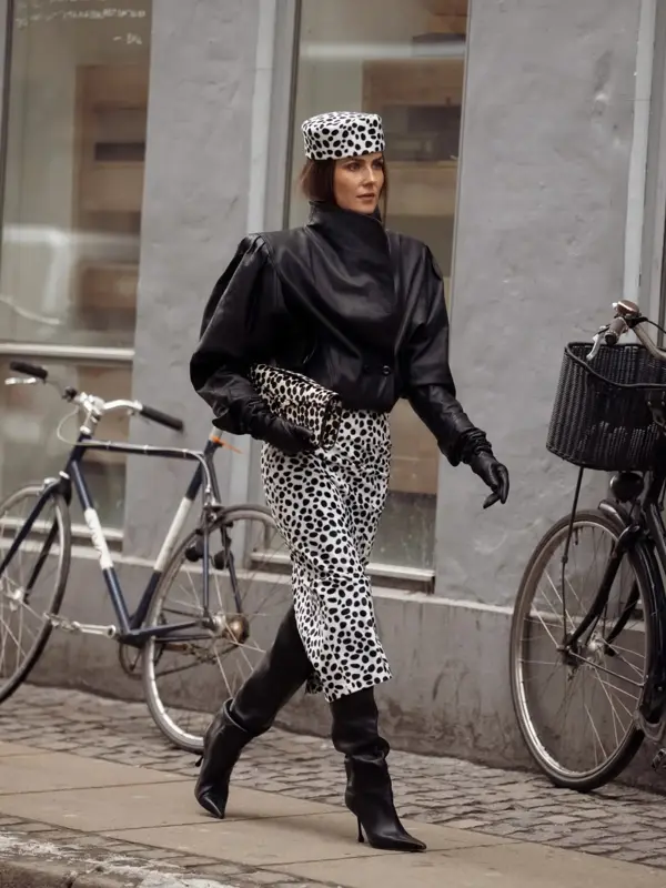 Nina i sort skinnjakke, prikkete hatt og skjørt og sorte støvletter.