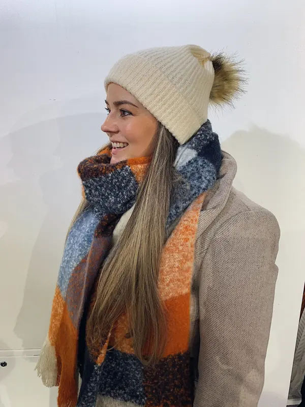 ansatt hos vero moda viser frem lys lue med dusk og fargerikt skjerf