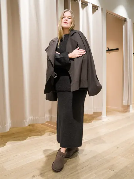 Dame i brun cape over genser ogs kjørt i strikk og brune uggs