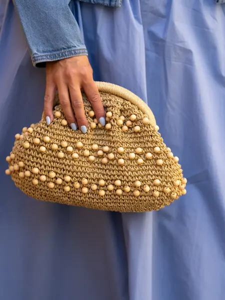 Hånd holder beige veske med perler