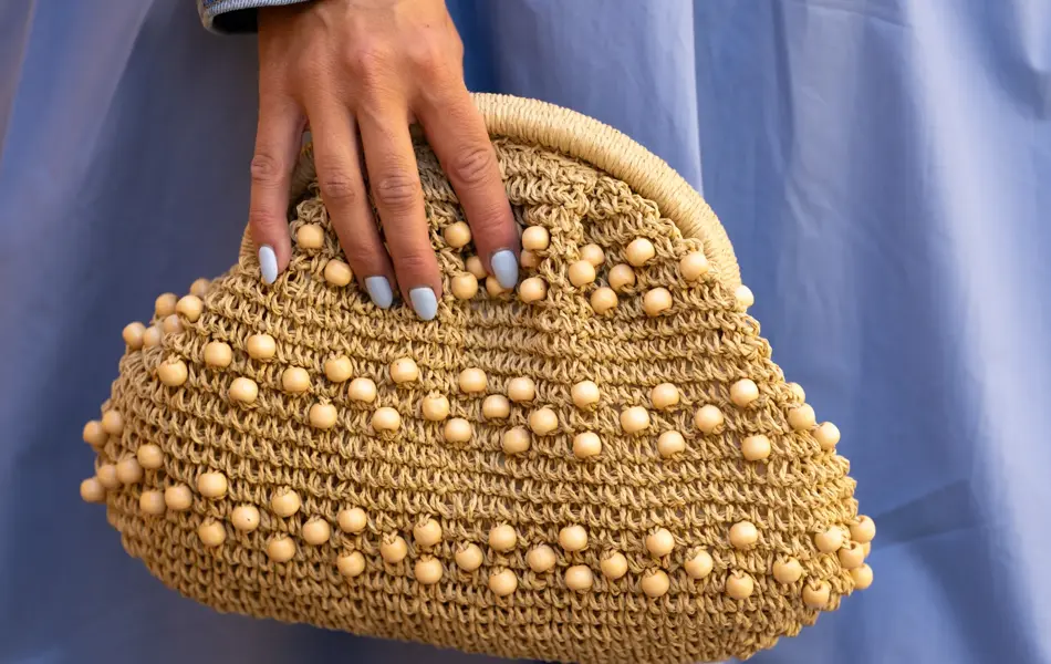 Hånd holder beige veske med perler