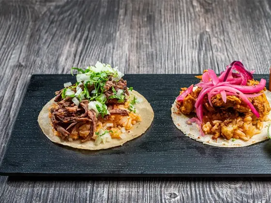Brett med to ulike taco retter med saus og lime på siden