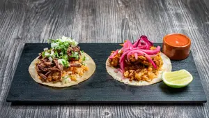 Brett med to ulike taco retter med saus og lime på siden