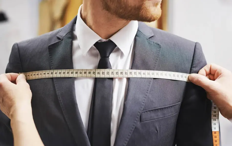 Mann i dress og noen som tar mål av dressen