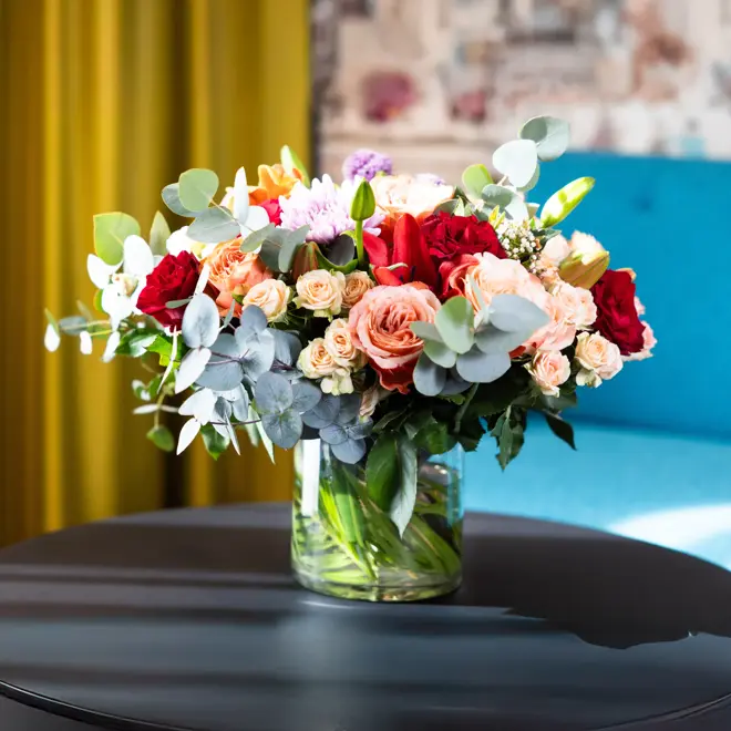 Fargerike blomster i en vase på et bord