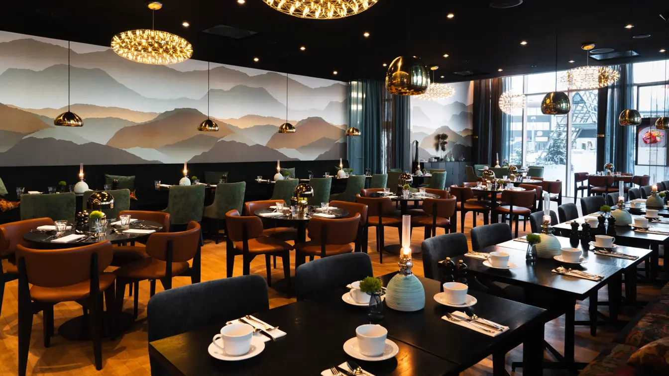 Restaurant med firkantede og runde bord, mørk farge på møbler og interiør.