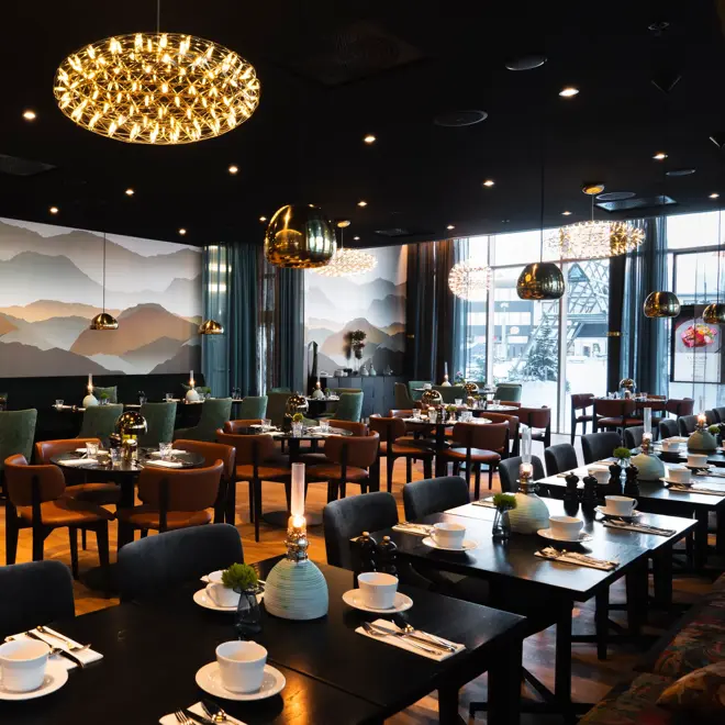 Restaurant med firkantede og runde bord, mørk farge på møbler og interiør.