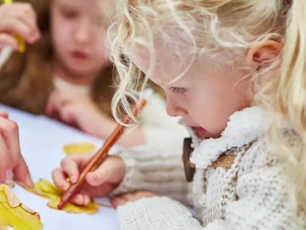 En jente tegner rundt et blad. Foto.
