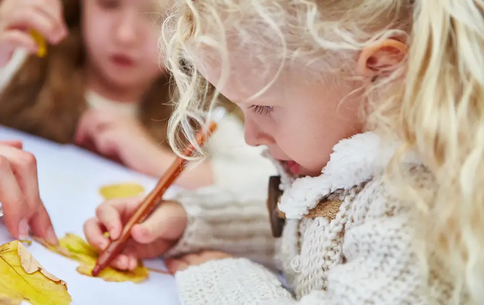 En jente tegner rundt et blad. Foto.