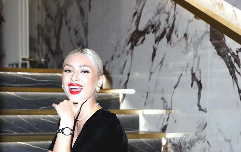 Dame med svart fløyelskjole sitter i mørk marmortrapp og smiler til kamera