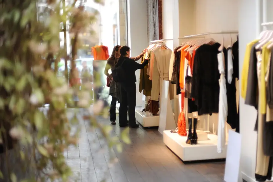 To damer som ser på klær inne i en klesbutikk.