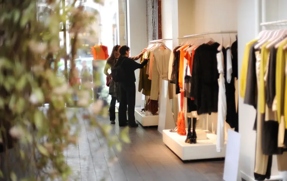 To damer som ser på klær inne i en klesbutikk.