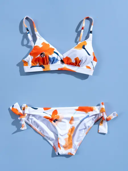 Hvit og orange blomstrete bikini på blå bakgrunn