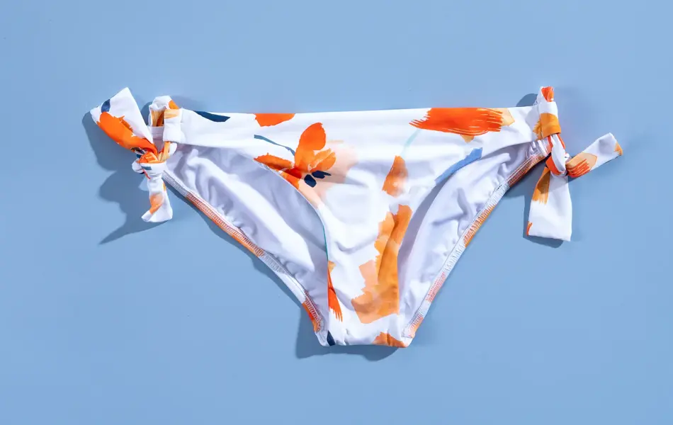 Hvit og orange blomstrete bikini på blå bakgrunn