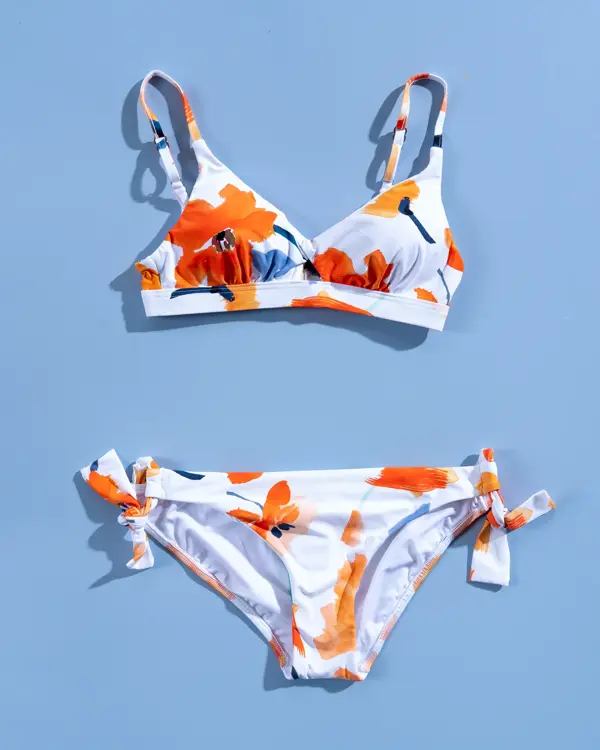Hvit og orange blomstrete bikini på blå bakgrunn
