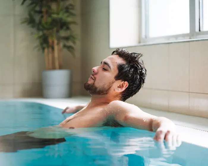 Mann som slapper av i bassenget på Vestkanten Spa