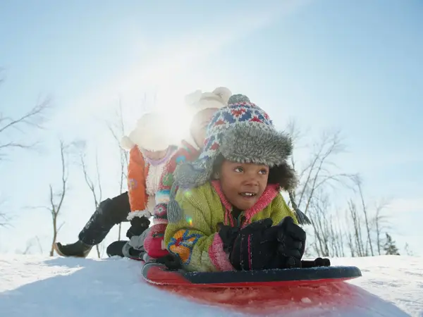 Tre barn som skal ake i snøen