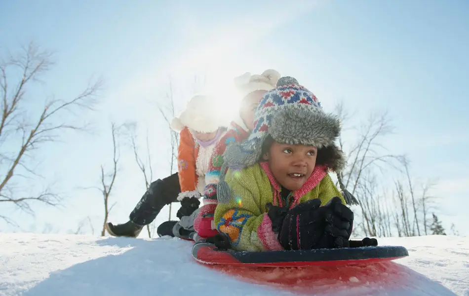 Tre barn som skal ake i snøen