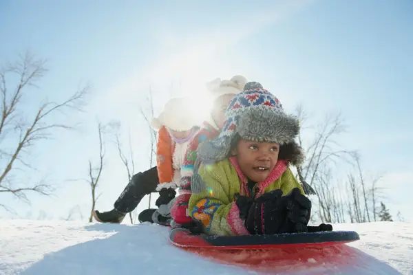 Tre barn som skal ake i snøen
