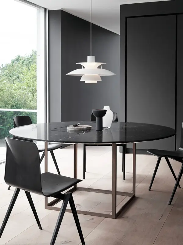Hvit retrolampe PH5 henger over et sort spisebord.