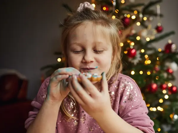 Happy smiling little girl eating a gingerbread