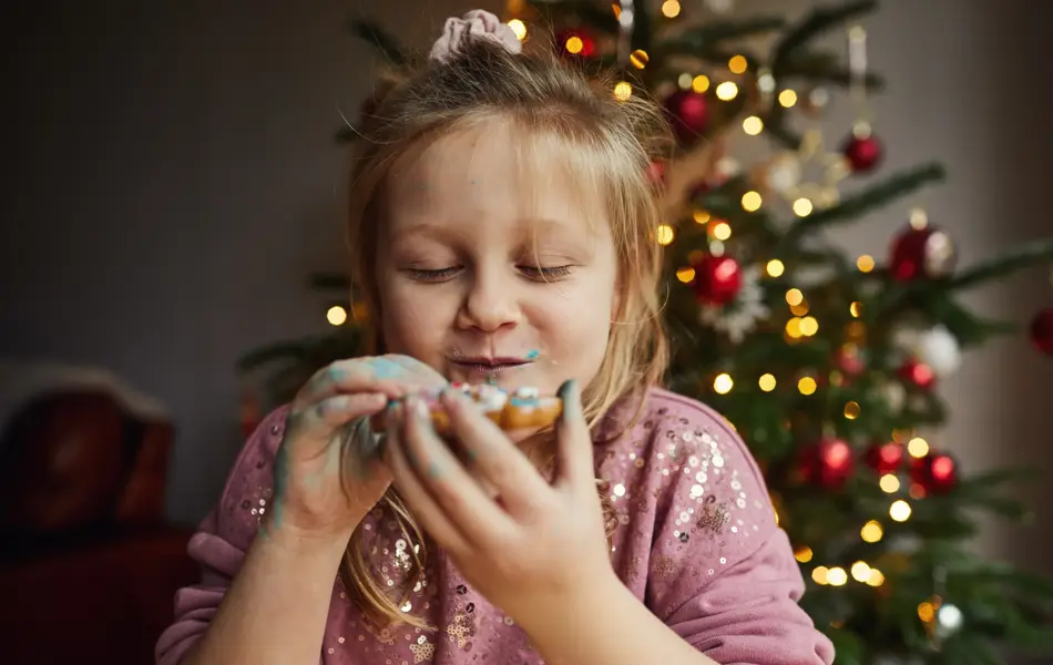 Happy smiling little girl eating a gingerbread