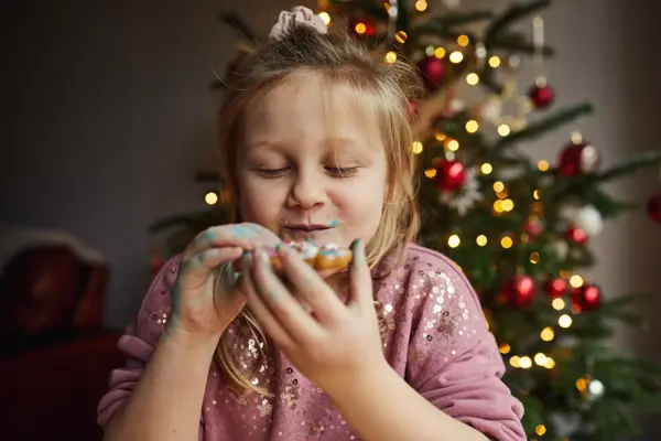 Happy smiling little girl eating a gingerbread