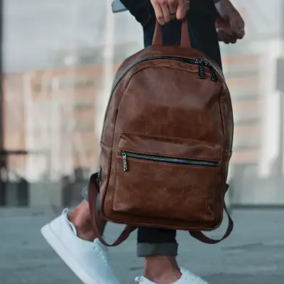 dame som holder en brun lær ryggsekk