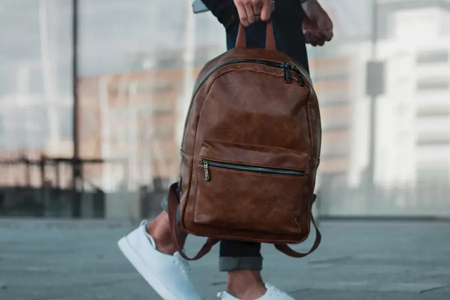 dame som holder en brun lær ryggsekk