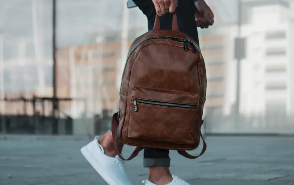 dame som holder en brun lær ryggsekk