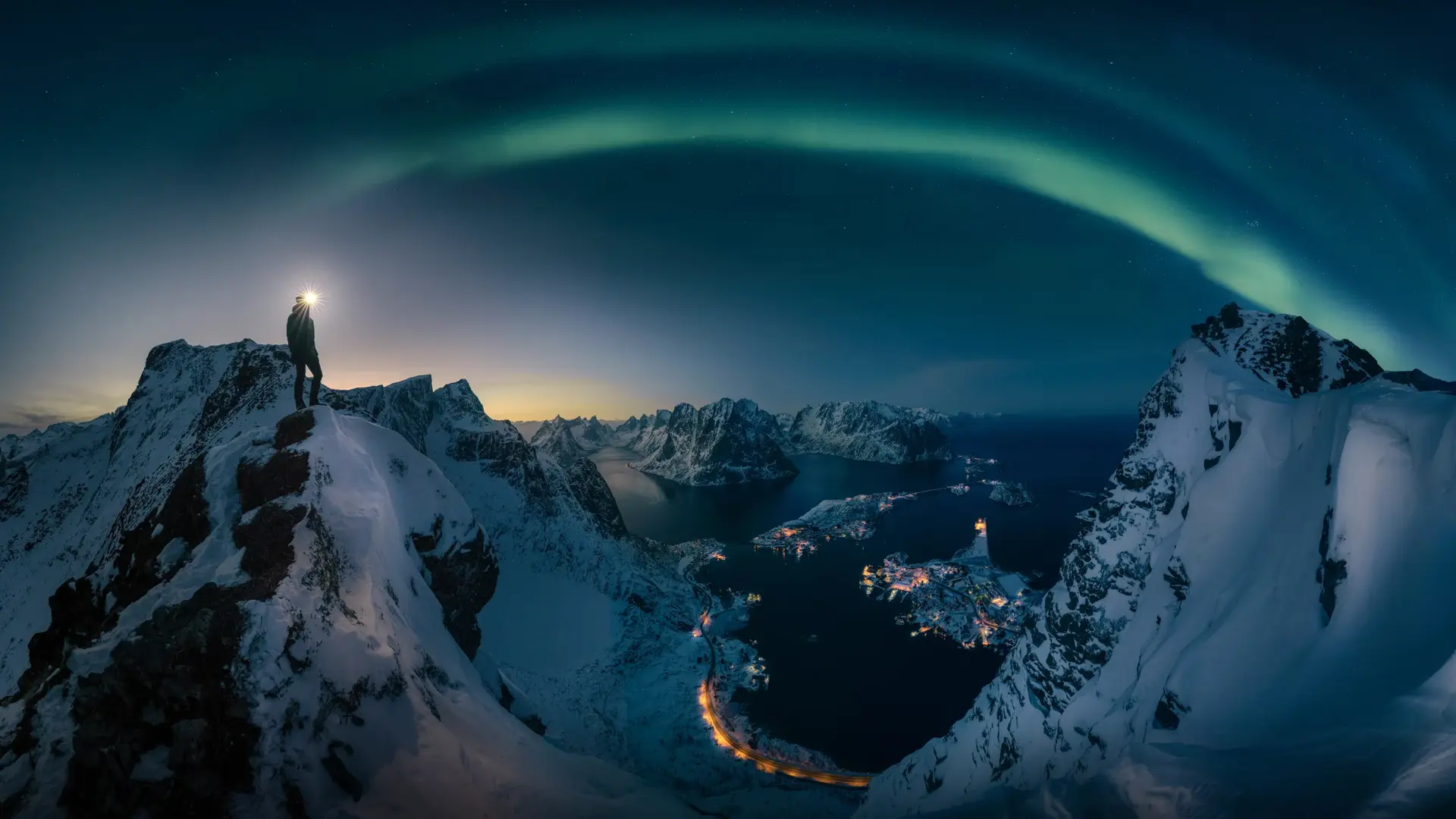 A man hiking on Reinebrigen, mountain in Lofoten Norway , Northern light over the mountain