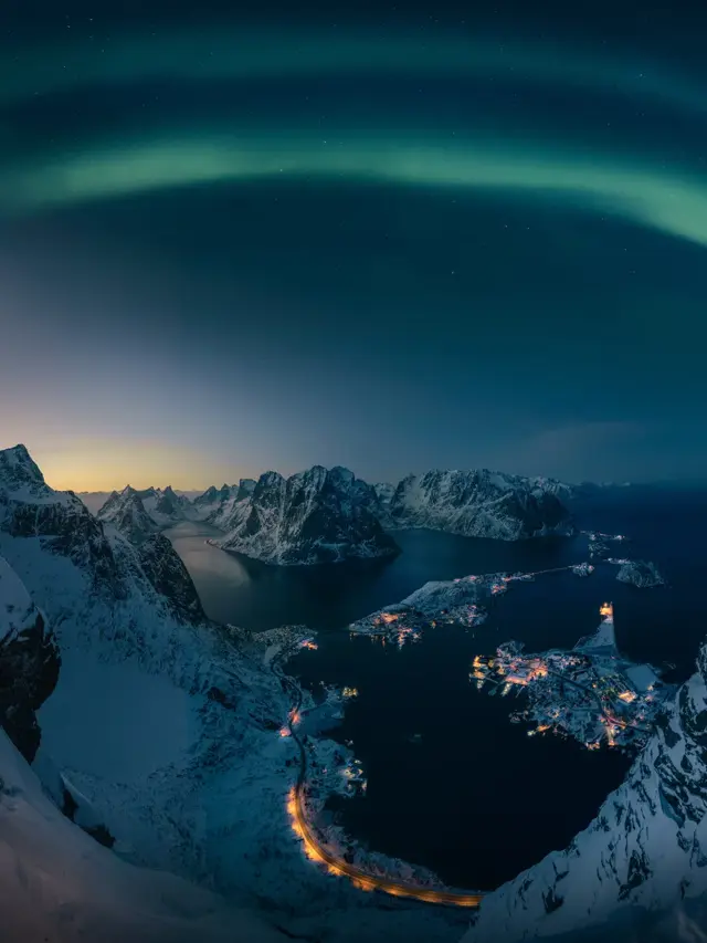 Man skuer utover vakkert nordlys fra Reinebrigen i Lofoten