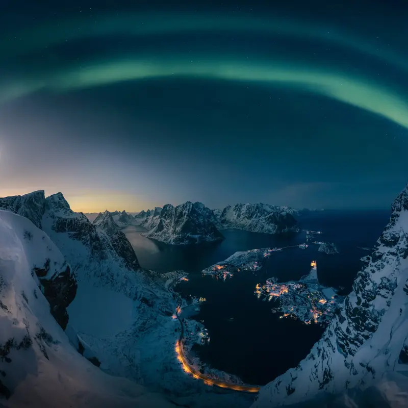 A man hiking on Reinebrigen, mountain in Lofoten Norway , Northern light over the mountain