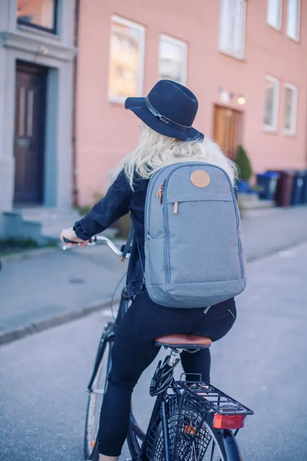 Jente med sekk sykler på en vei