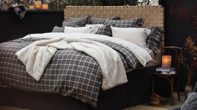 Seng med rutete sengesett og mørke vegger