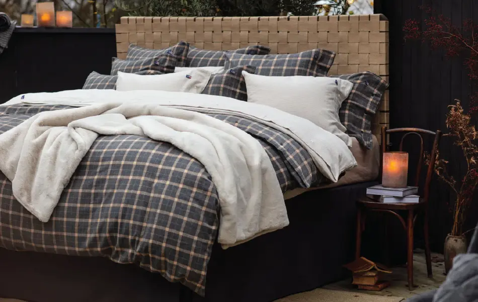 Seng med rutete sengesett og mørke vegger