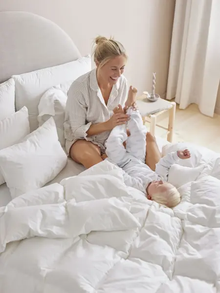 Mor og gutt som leker i en seng