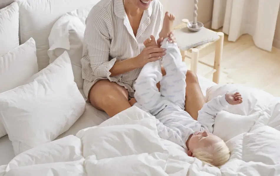 Mor og gutt som leker i en seng