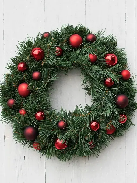 Julekrans med julekuler på henger på vegg