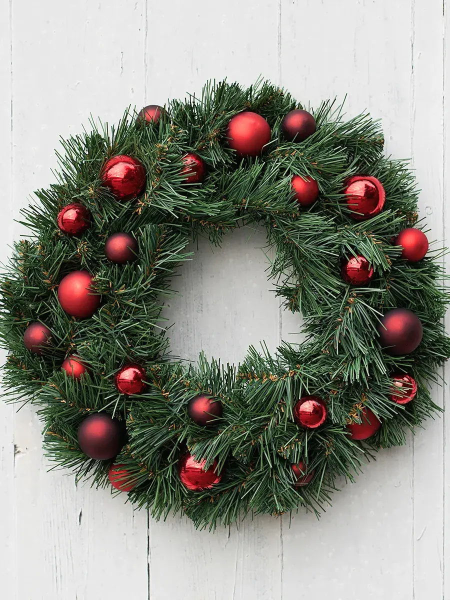 Julekrans med julekuler på henger på vegg