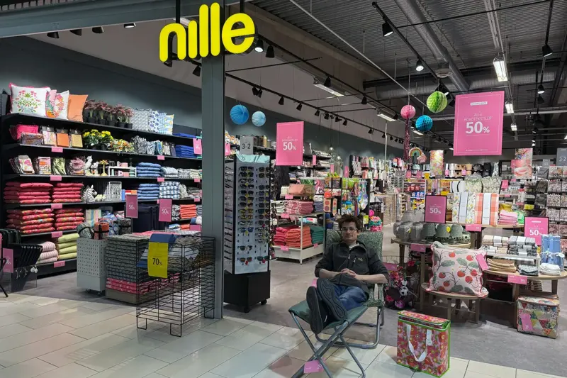 Mann som sitter i en hagestol foran butikken