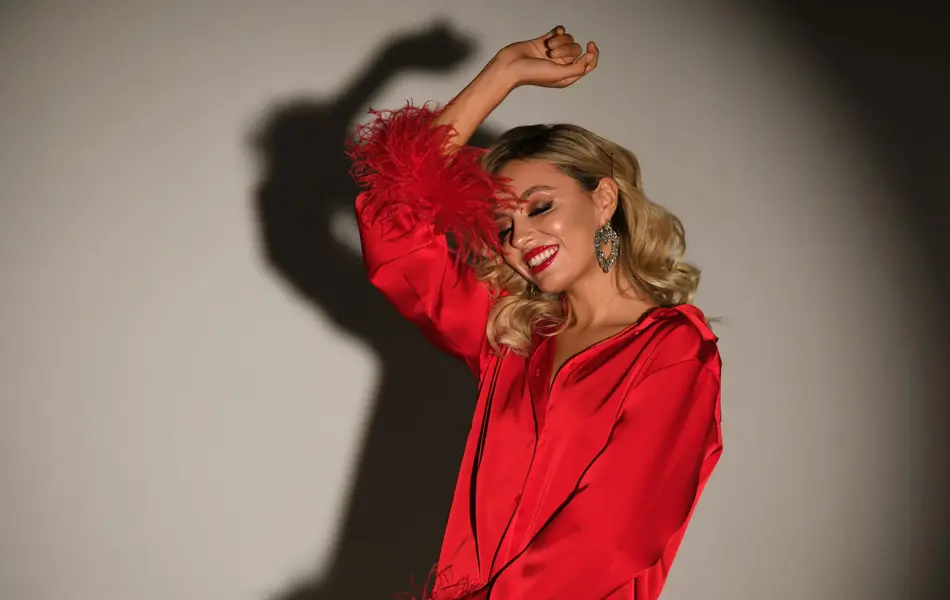 Dame med rød satengkjole danser for en grå vegg