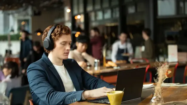mann som sitter på kafé med headset og laptop