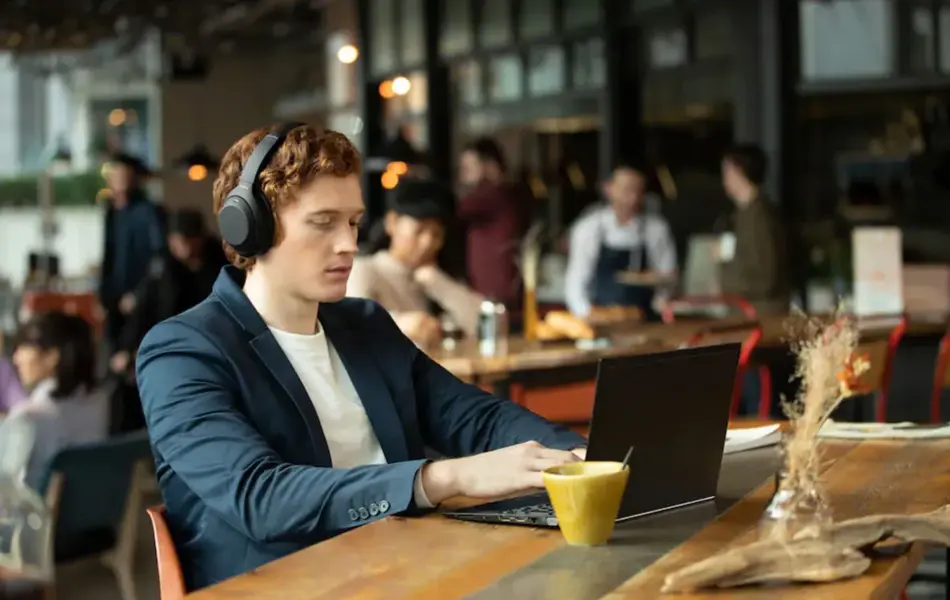 mann som sitter på kafé med headset og laptop