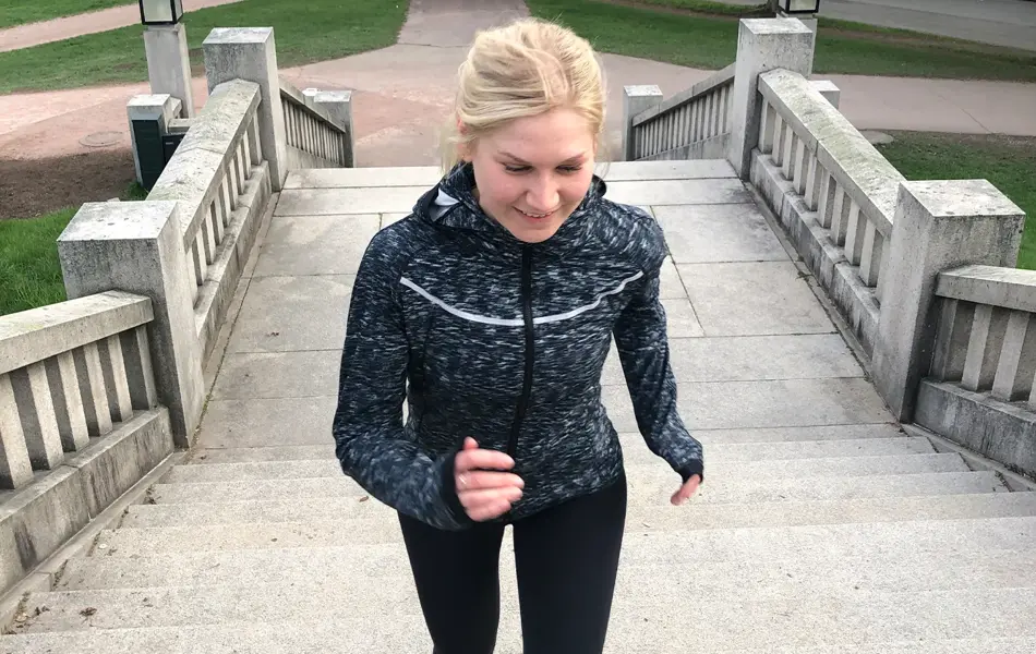 Dame i treningstøy som jogger opp en trapp ute.