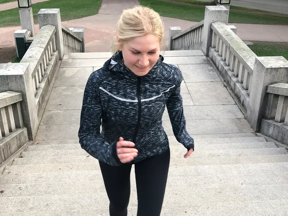 Dame i treningstøy som jogger opp en trapp ute.