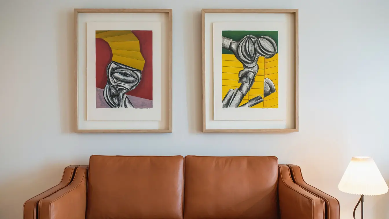 Lysebrun skinnsofa, hvite vegger og to store fargerike bilder. I suite på Thon Hotel Norge i Kristiansand.