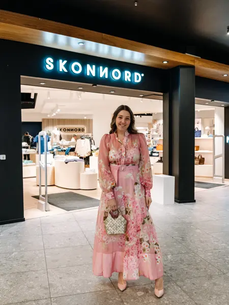 dame i kjole står foran butikk