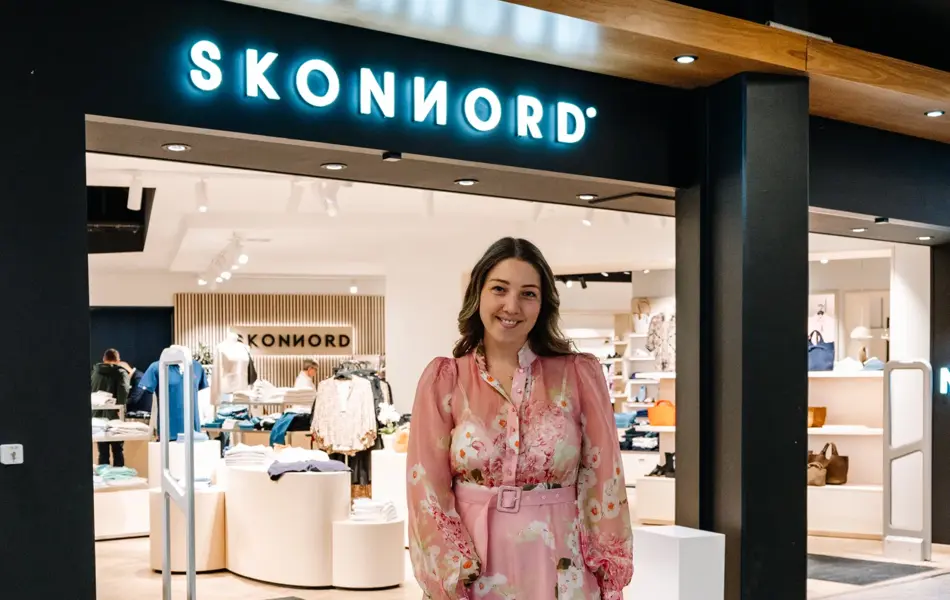 dame i kjole står foran butikk